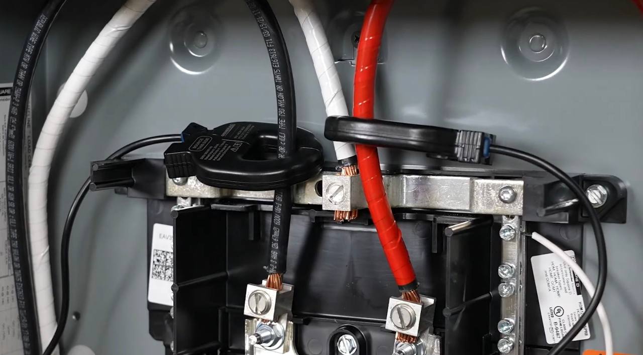Split-core current transformer clamps installed on the main service entrance conductors at the panel lugs
